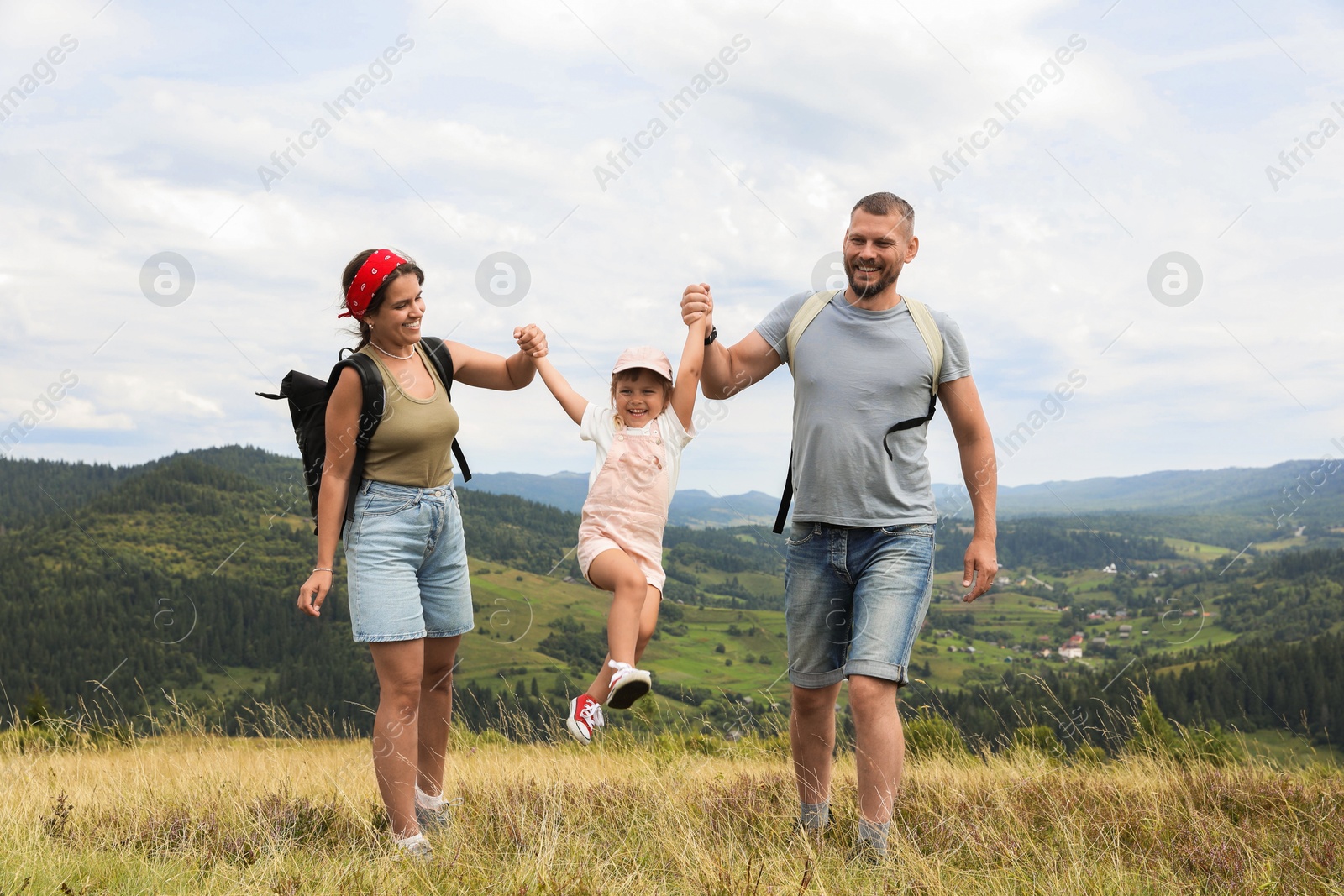 Photo of Happy family with backpacks travelling in mountains. Active tourism