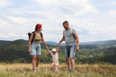 Photo of Happy family with backpacks travelling in mountains. Active tourism