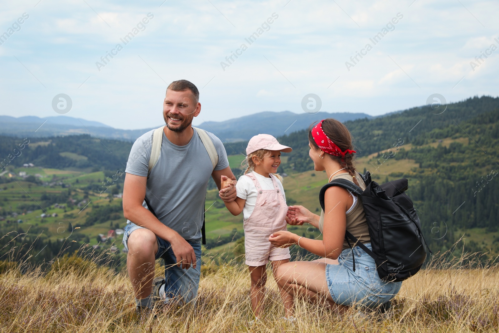 Photo of Happy family with backpacks travelling in mountains. Active tourism