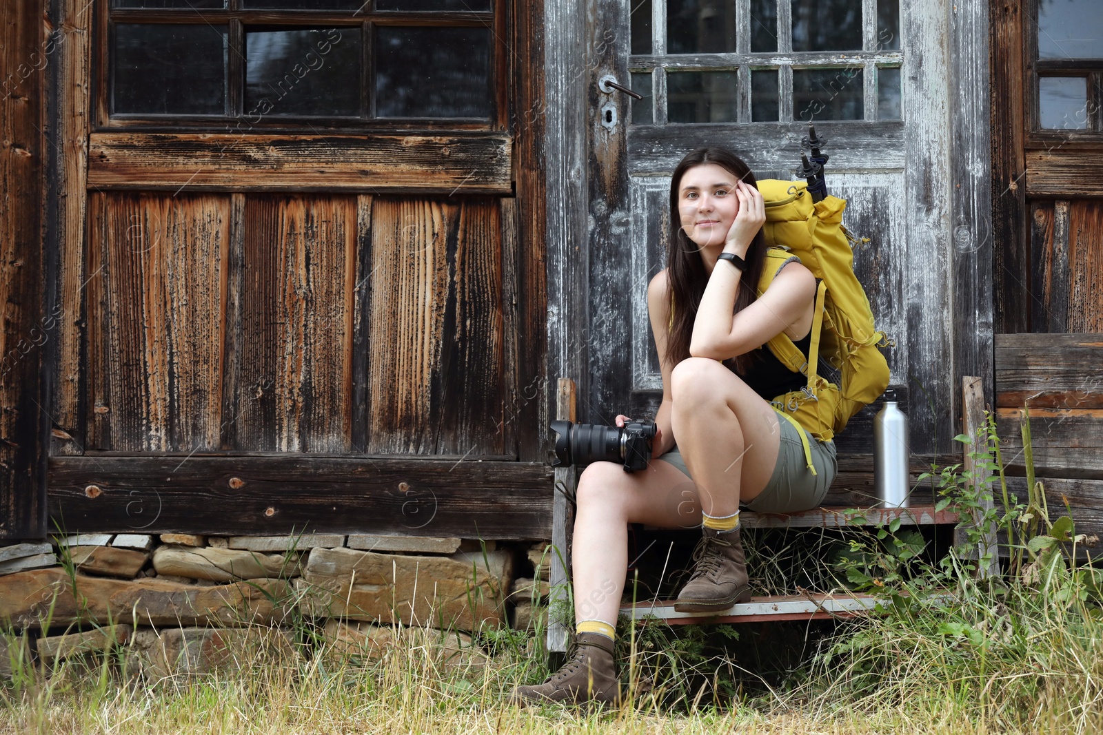 Photo of Young hiker with backpack near old wooden building outdoors, space for text