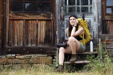 Photo of Young hiker with backpack near old wooden building outdoors, space for text