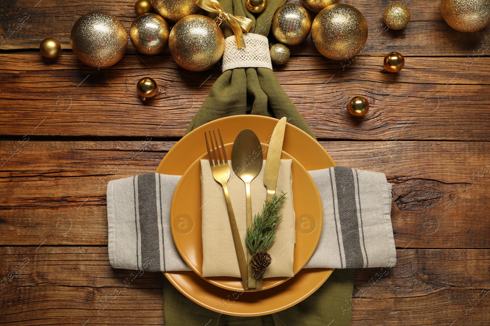 Photo of Christmas place setting with plates, cutlery and festive decor on wooden table, flat lay