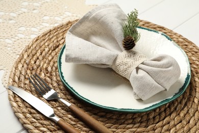 Photo of Christmas place setting with plate, cutlery and decor on white wooden table, closeup