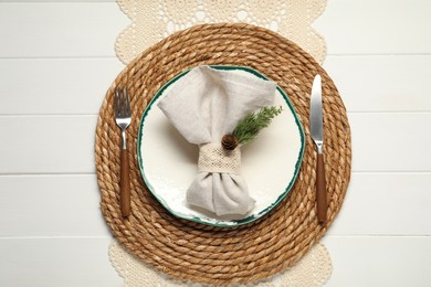 Photo of Christmas place setting with plate, cutlery and decor on white wooden table, top view