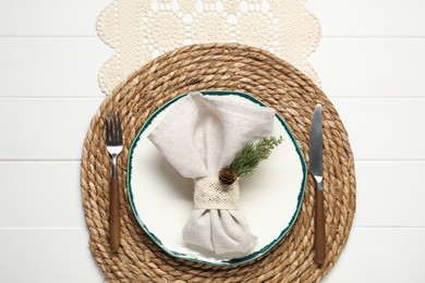 Photo of Christmas place setting with plate, cutlery and decor on white wooden table, top view