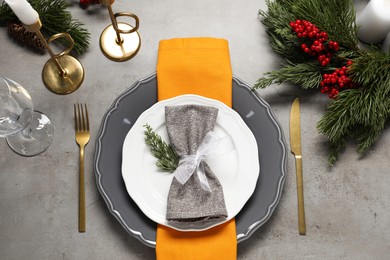 Photo of Christmas place setting with festive decor on grey table, flat lay