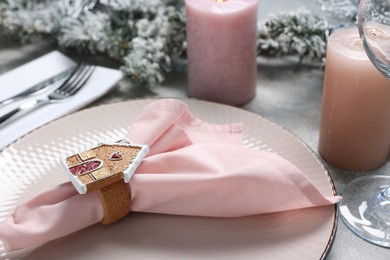 Photo of Christmas place setting with plate, napkin and festive decor on grey table, closeup