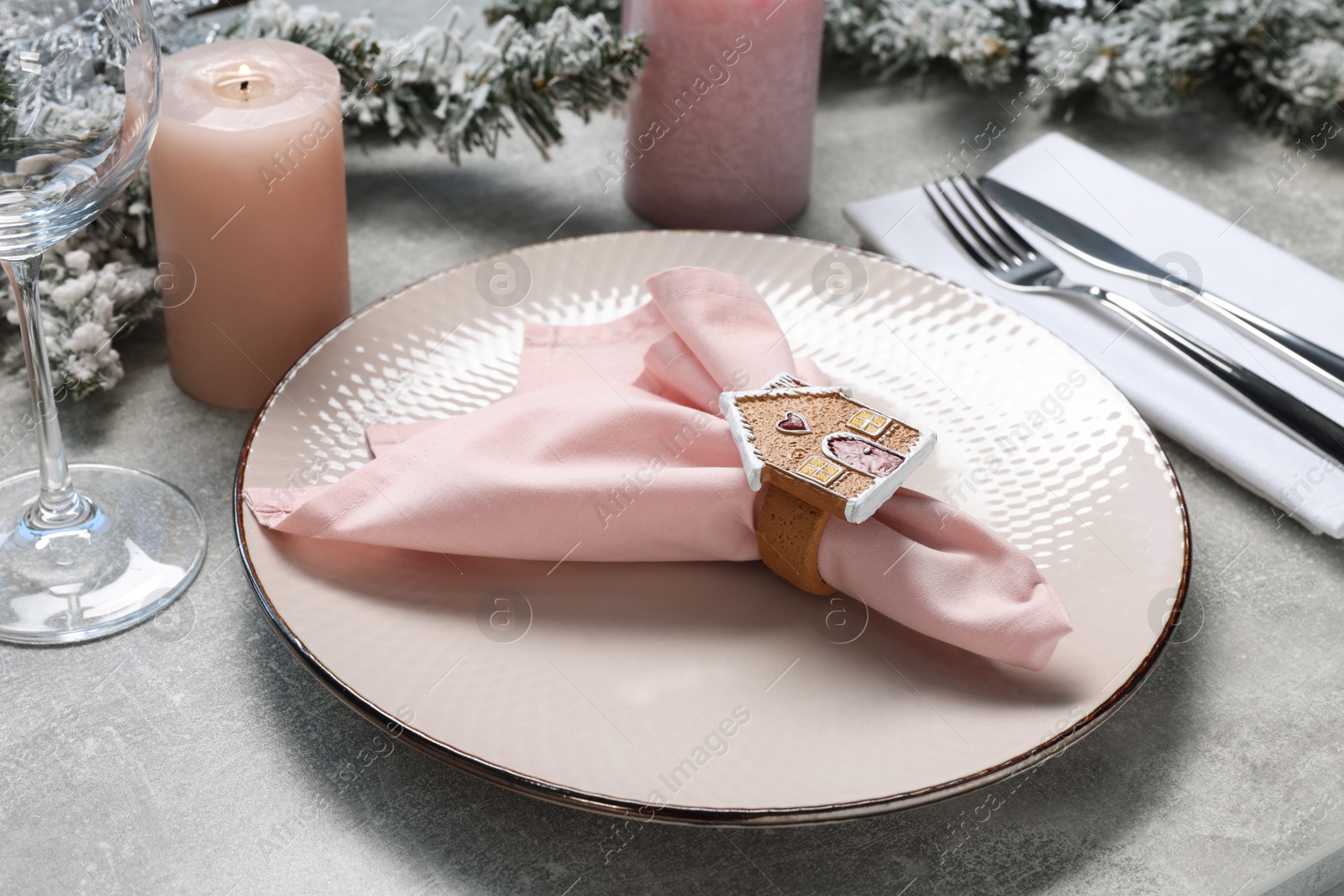 Photo of Christmas place setting with plate, napkin, cutlery and festive decor on grey textured table, closeup