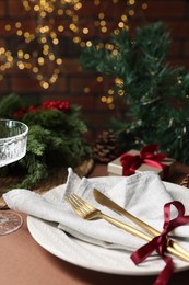 Photo of Christmas place setting with plate, napkin, cutlery and festive decor on brown table