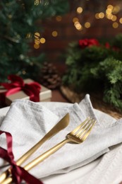 Photo of Christmas place setting with plate, napkin, cutlery and festive decor on table, closeup