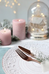 Photo of Christmas place setting with plate, cutlery and festive decor on table, closeup