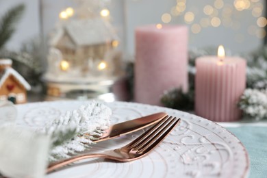 Photo of Christmas place setting with plate, cutlery and festive decor on table, closeup