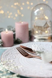 Photo of Christmas place setting with plate, cutlery and festive decor on table, closeup