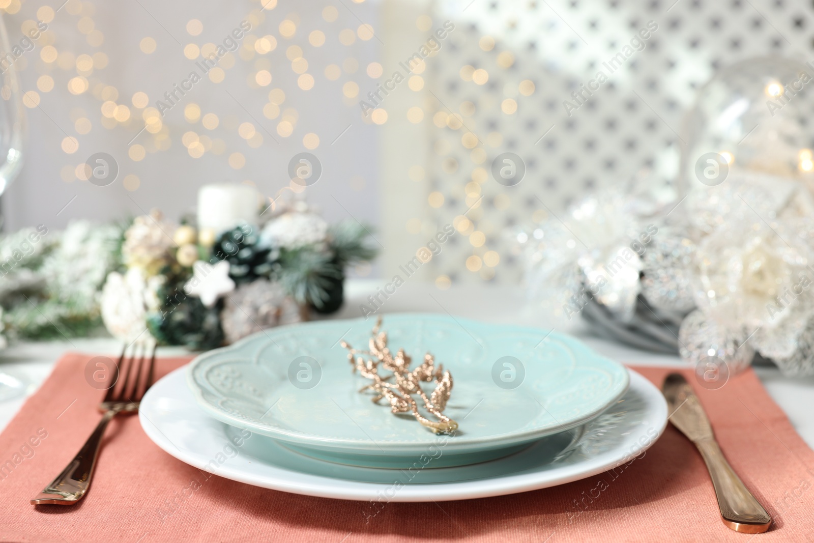 Photo of Christmas place setting with plates, cutlery and festive decor on table, closeup