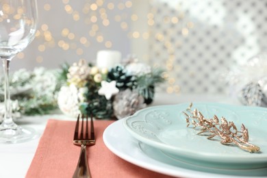 Photo of Christmas place setting with plates, fork and festive decor on table, closeup