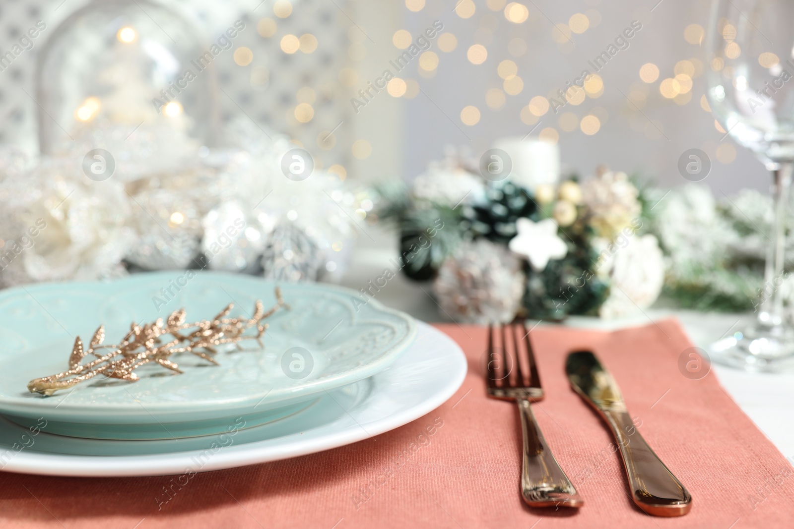 Photo of Christmas place setting with plates, cutlery and festive decor on table, closeup