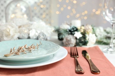 Photo of Christmas place setting with plates, cutlery and festive decor on table, closeup