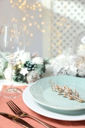 Photo of Christmas place setting with plates, cutlery and festive decor on table, closeup