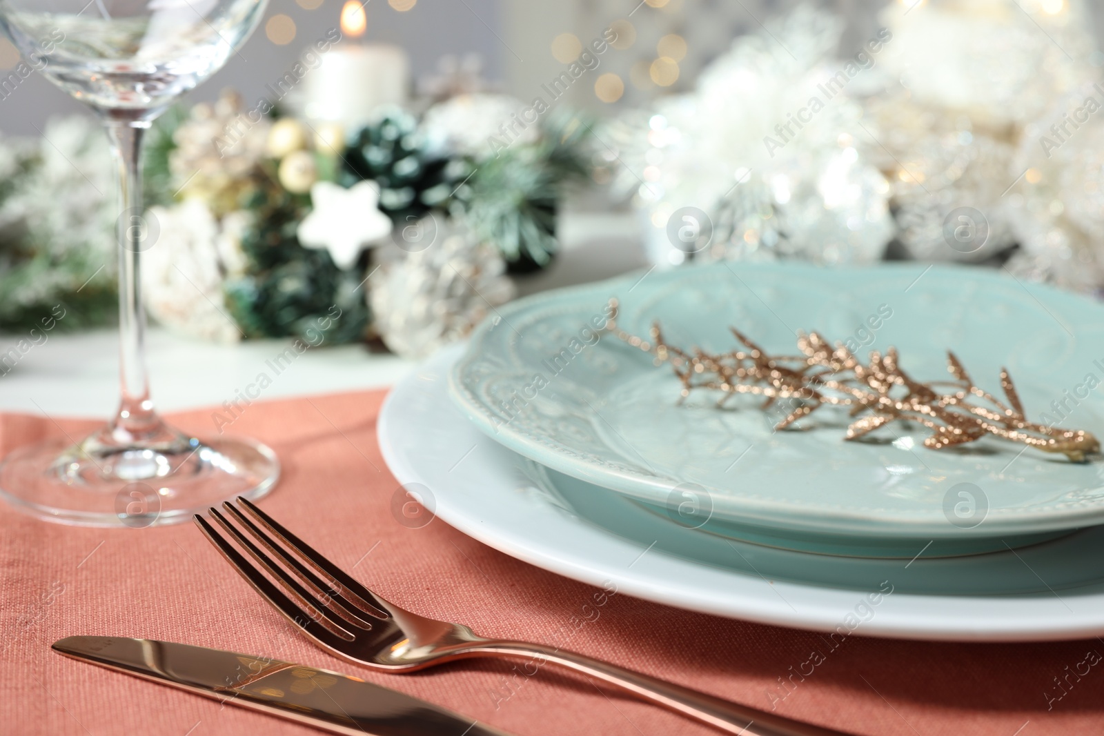 Photo of Christmas place setting with plates, cutlery and festive decor on table, closeup