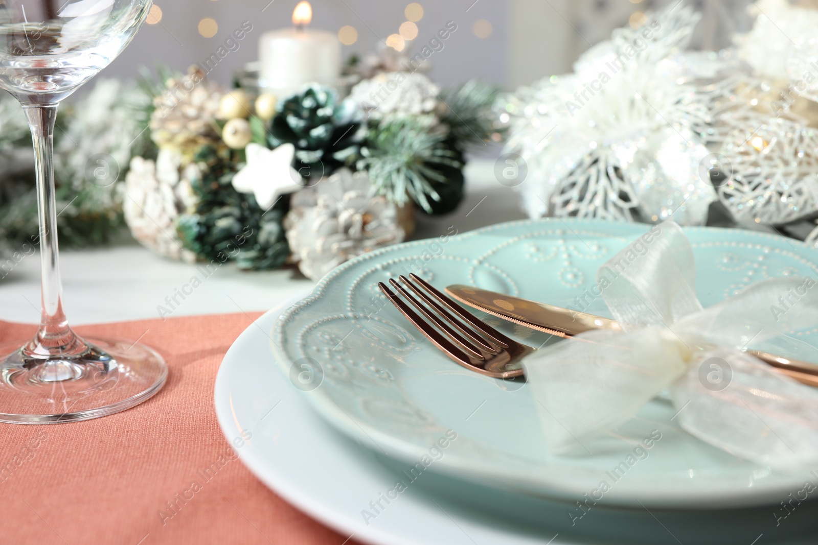 Photo of Christmas place setting with plates, cutlery and festive decor on table, closeup