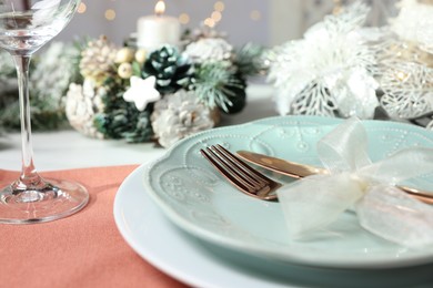 Photo of Christmas place setting with plates, cutlery and festive decor on table, closeup