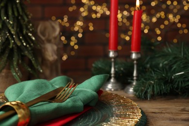 Photo of Christmas place setting with festive decor on wooden table, closeup