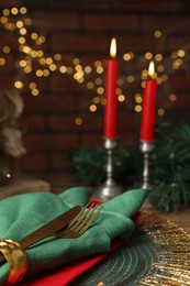 Photo of Christmas place setting with napkin, cutlery and festive decor on table, closeup