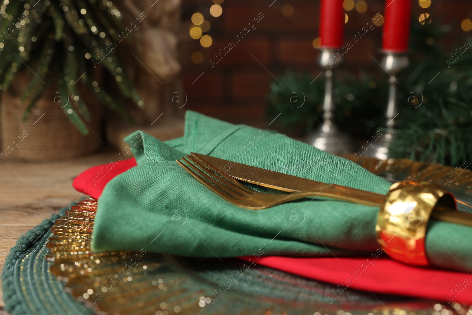 Photo of Christmas place setting with napkin, cutlery and festive decor on wooden table, closeup