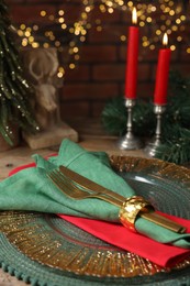 Photo of Christmas place setting with napkin, cutlery and festive decor on table, closeup