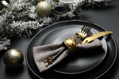 Photo of Plates, cutlery and Christmas decor on black table, closeup