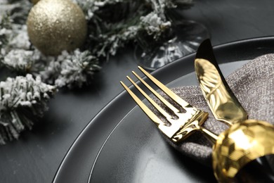 Photo of Plates, cutlery and Christmas decor on black table, closeup