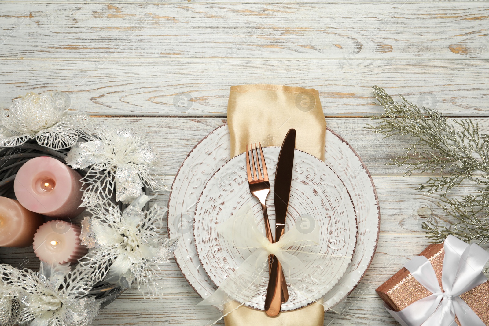 Photo of Christmas place setting with plates, cutlery and festive decor on wooden table, top view