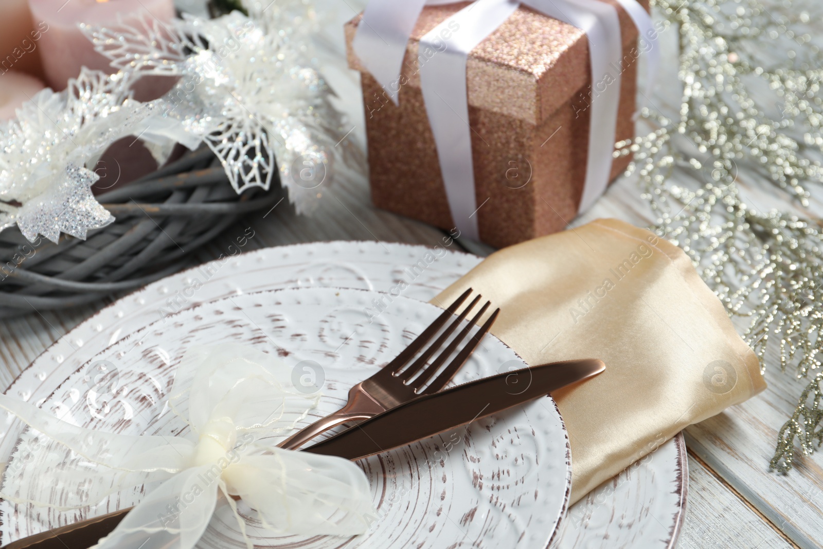 Photo of Christmas place setting with plates, cutlery and festive decor on wooden table, closeup