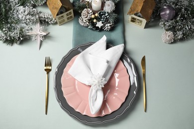 Photo of Christmas table setting with plates, cutlery and festive decor on light grey background, top view