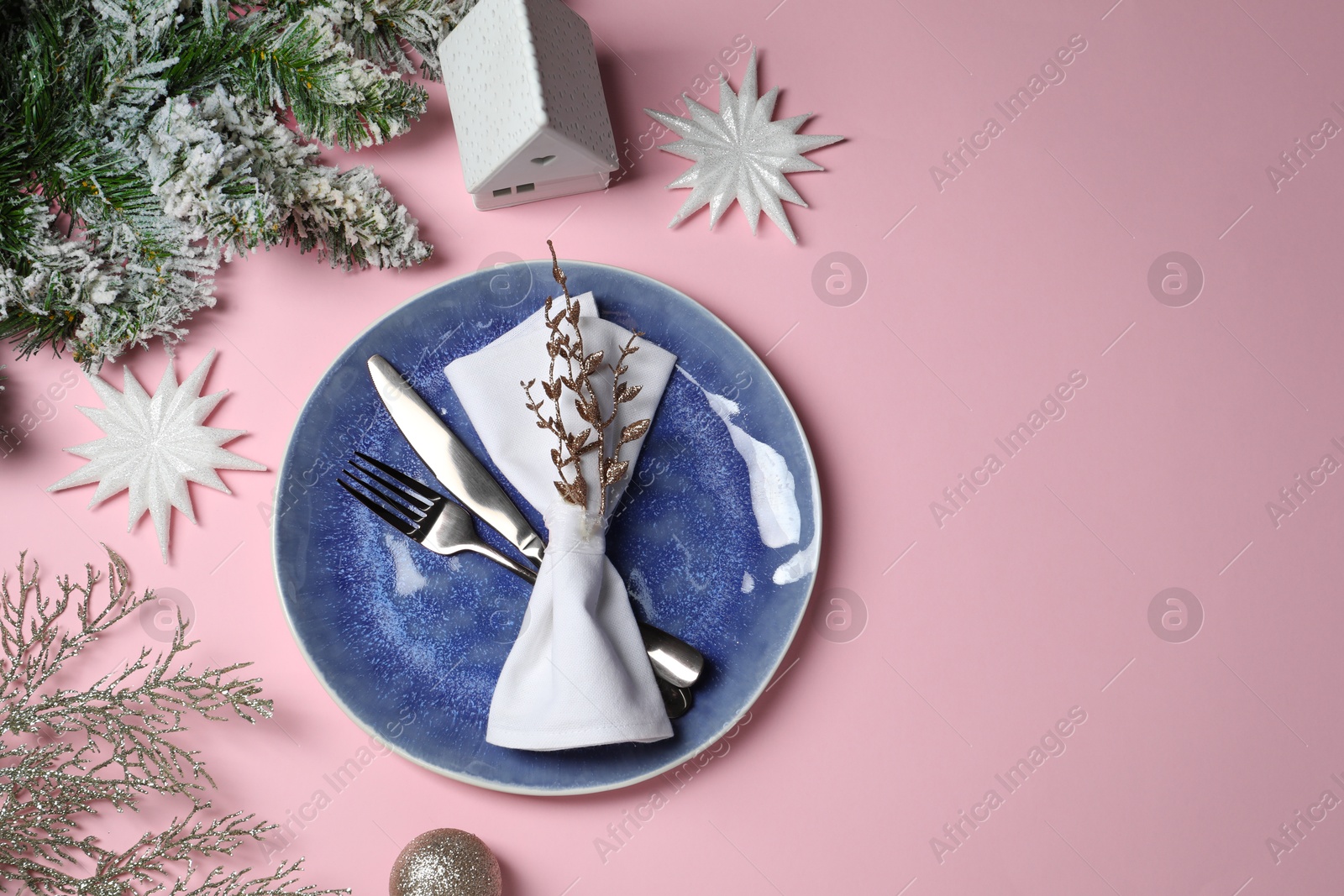 Photo of Christmas table setting with plate, cutlery and festive decor on pink background, top view. Space for text