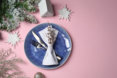 Photo of Christmas table setting with plate, cutlery and festive decor on pink background, top view. Space for text