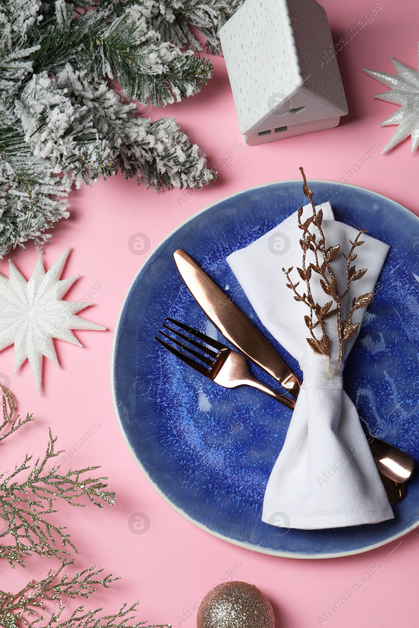 Photo of Christmas table setting with plate, cutlery and festive decor on pink background, top view