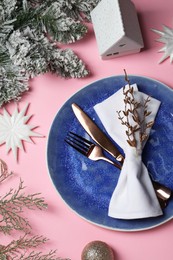 Photo of Christmas table setting with plate, cutlery and festive decor on pink background, top view