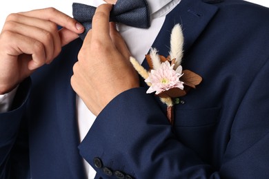 Photo of Groom in suit with stylish boutonniere on white background, closeup