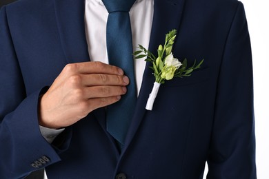 Photo of Groom in suit with stylish boutonniere on white background, closeup