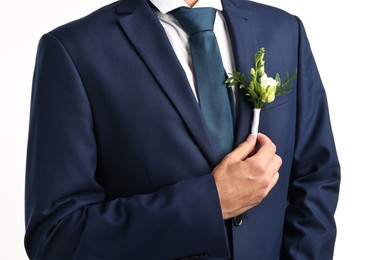 Photo of Groom in suit with stylish boutonniere on white background, closeup