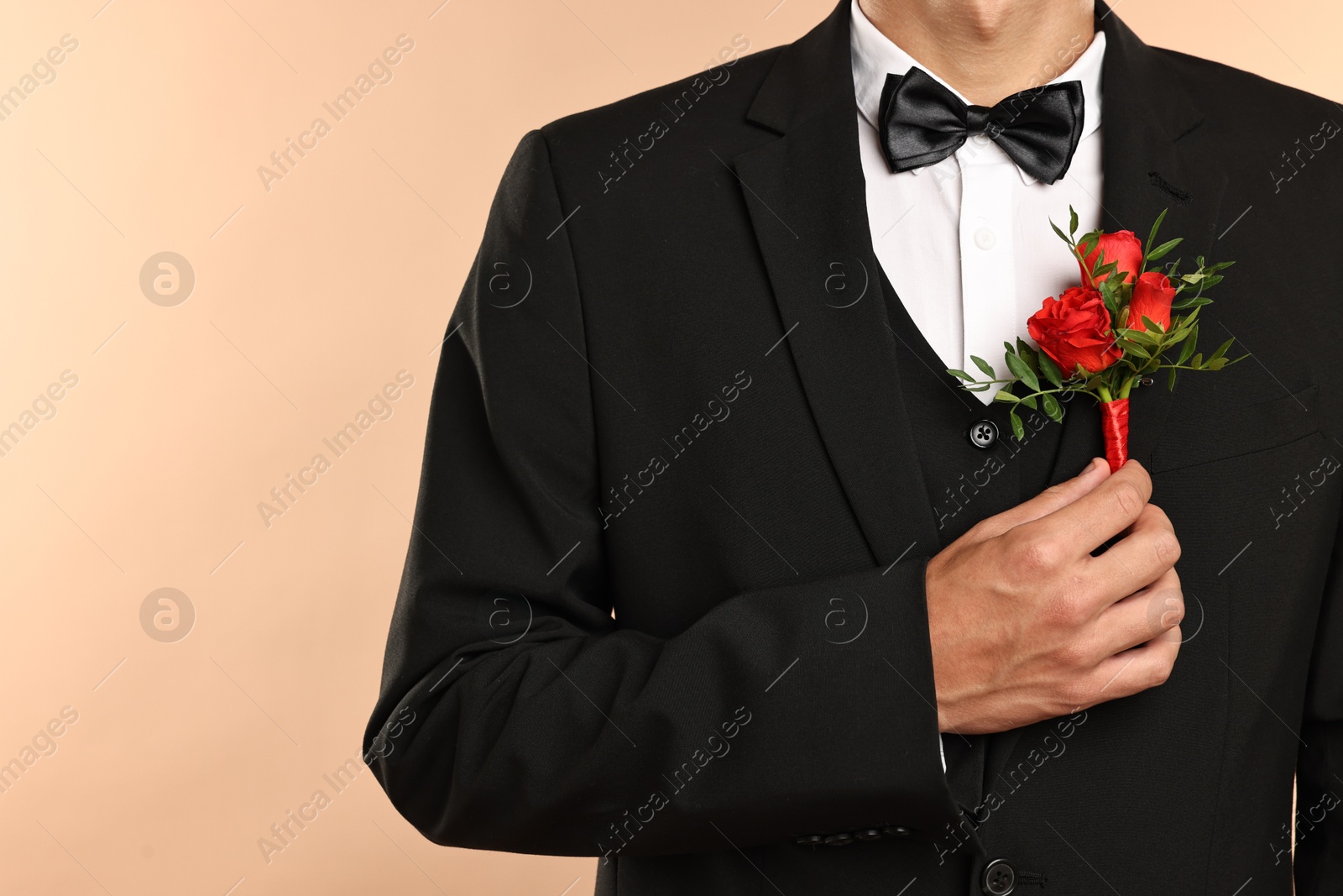 Photo of Groom in suit with stylish boutonniere on beige background, closeup. Space for text