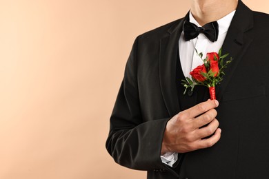 Photo of Groom in suit with stylish boutonniere on beige background, closeup. Space for text