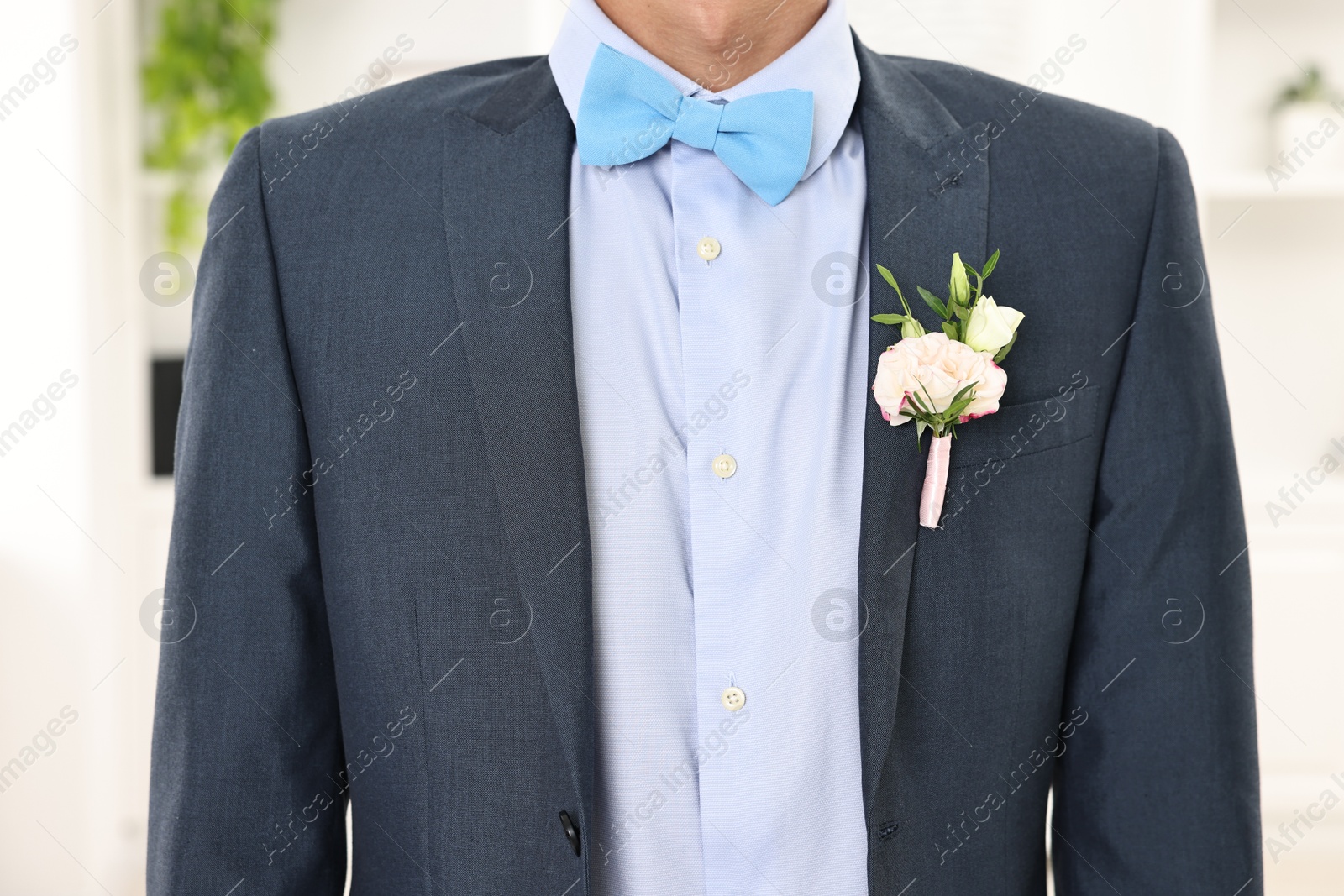 Photo of Groom in suit with stylish boutonniere indoors, closeup