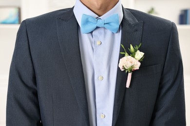 Photo of Groom in suit with stylish boutonniere indoors, closeup