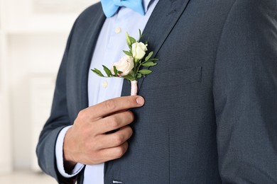 Photo of Groom in suit with stylish boutonniere indoors, closeup