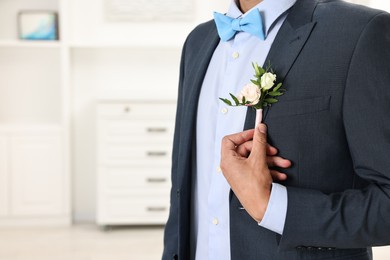 Photo of Groom in suit with stylish boutonniere indoors, closeup. Space for text