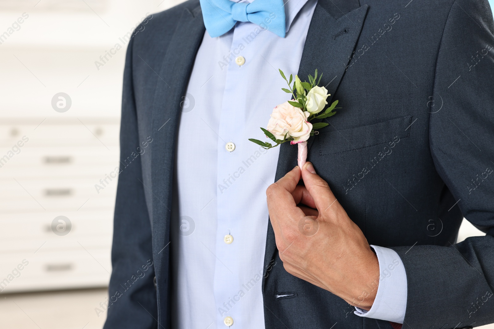 Photo of Groom in suit with stylish boutonniere indoors, closeup