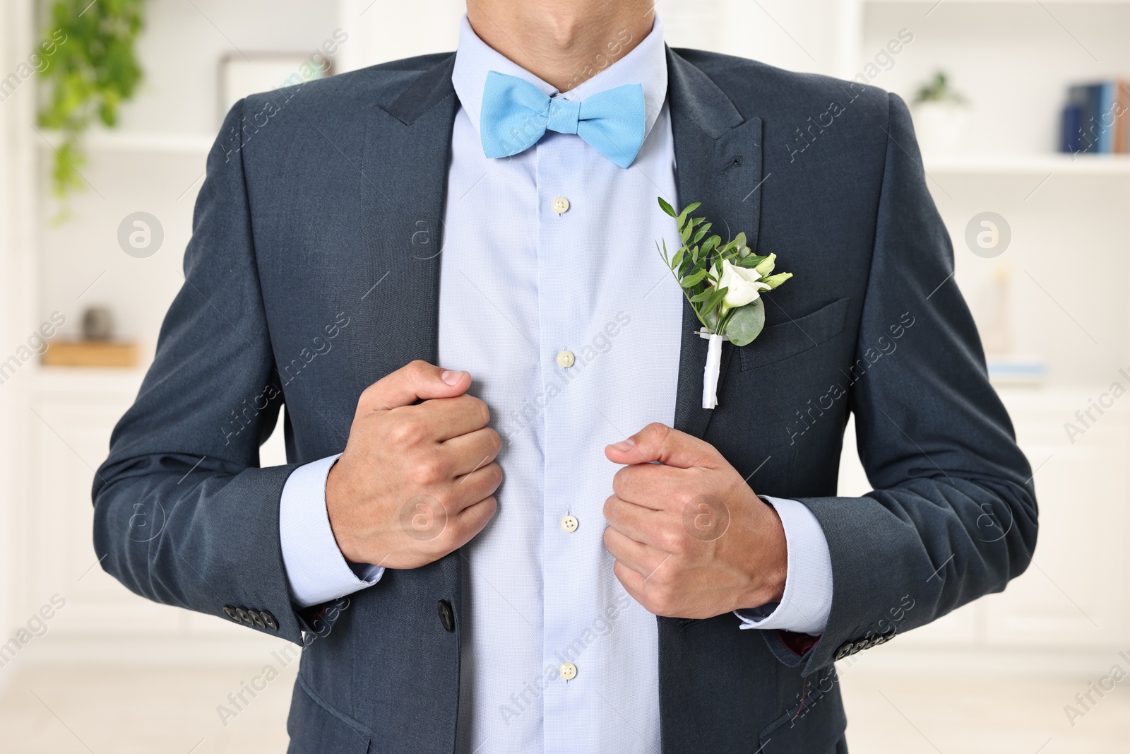 Photo of Groom in suit with stylish boutonniere indoors, closeup