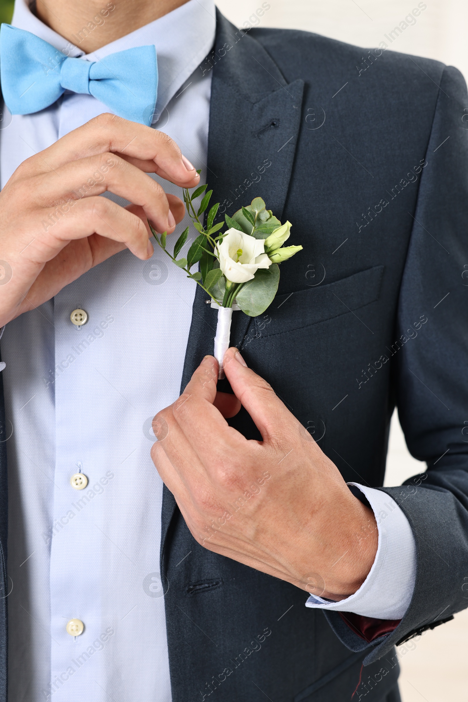 Photo of Groom in suit with stylish boutonniere indoors, closeup